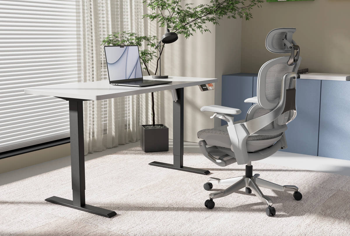 Shappa MS1 electric standing desk frame with white tabletop, laptop and ergonomic mesh office chair in a home office setting