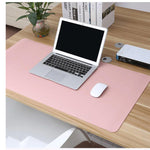 Pink dual-sided desk mat on a home office desk with a laptop, books and a plant