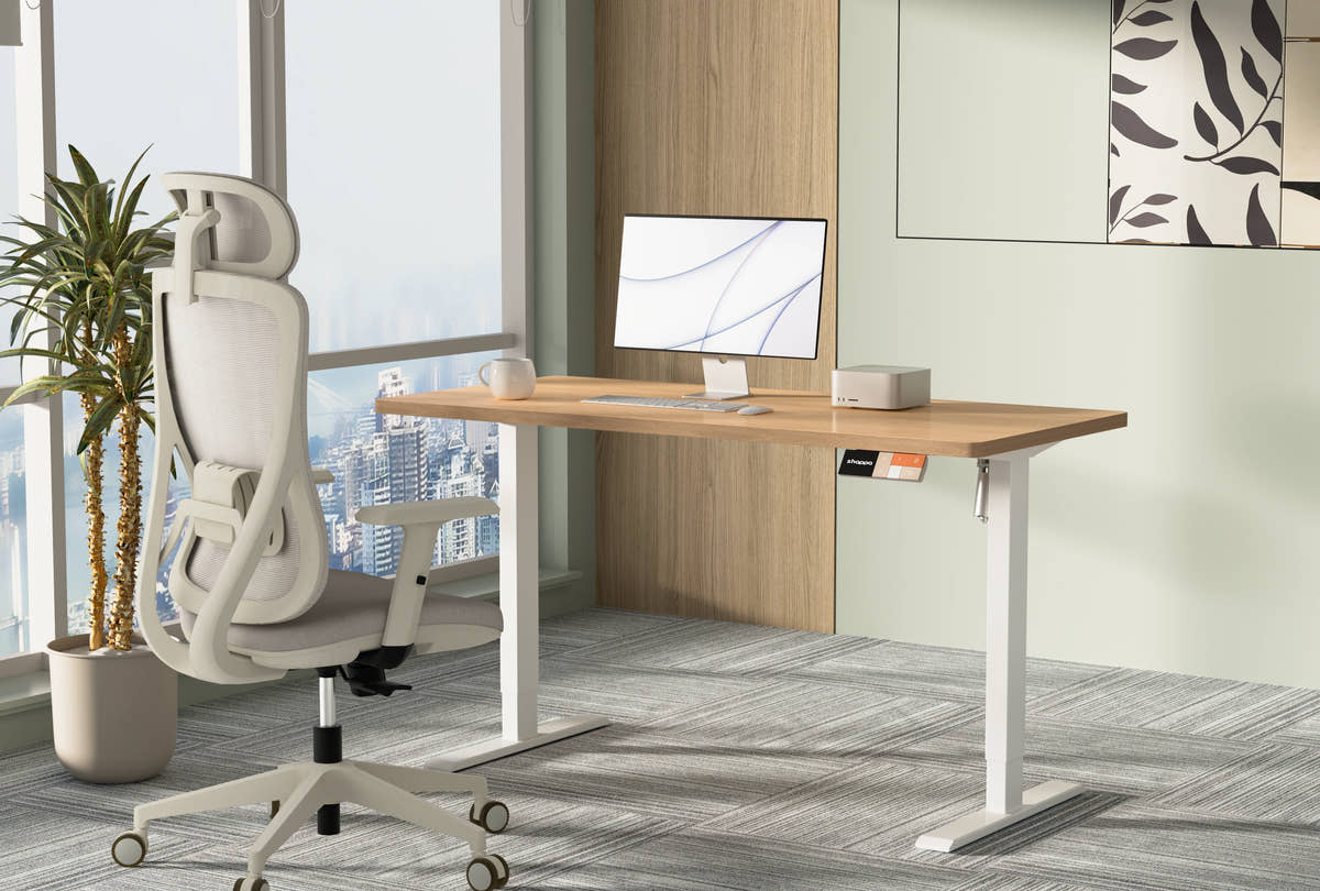 Shappa MS1 electric standing desk with oak tabletop and white frame, paired with a Shappa A7 ergonomic office chair in a high-rise office