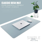 Light blue leather mouse pad and keyboard mat on a desk with a laptop and a small plant