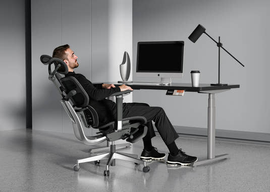 Man reclining in Shappa Spencer black ergonomic office chair for a break at his desk