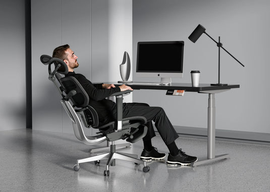 Man reclining in Shappa Spencer black ergonomic office chair for a break at his desk