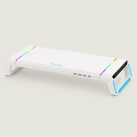 White gaming monitor riser stand with RGB light strips, built-in USB ports, and modern cooling platform design on #E6E6DE background.